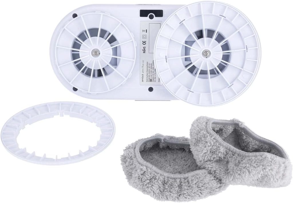 Une paire de pantoufles de robot amibot et un ventilateur blanc sur une surface grise.
