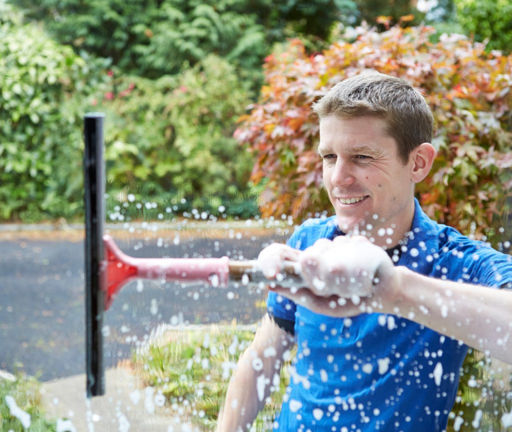 un homme pulvérisant de l'eau sur un jardin avec un tuyau.